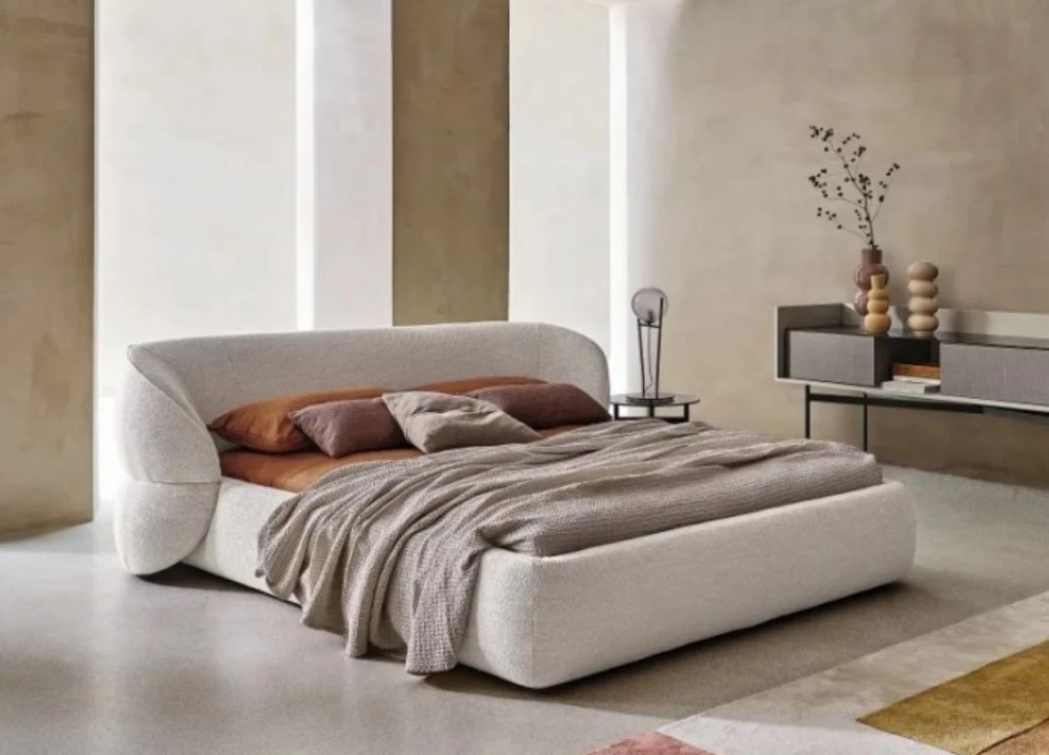 Κρεβάτι Ιταλικού design με στρογγυλό κεφαλάρι, ύφασμα & δέρμα, διαθέσιμο σε ποικιλία χρωμάτων. Ιδανικό για τοποθέτηση στο κέντρο του δωματίου. Σε λευκο μπουκλε υφασμα και χρωμα